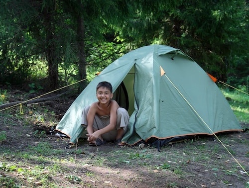 happy boy near camping tent