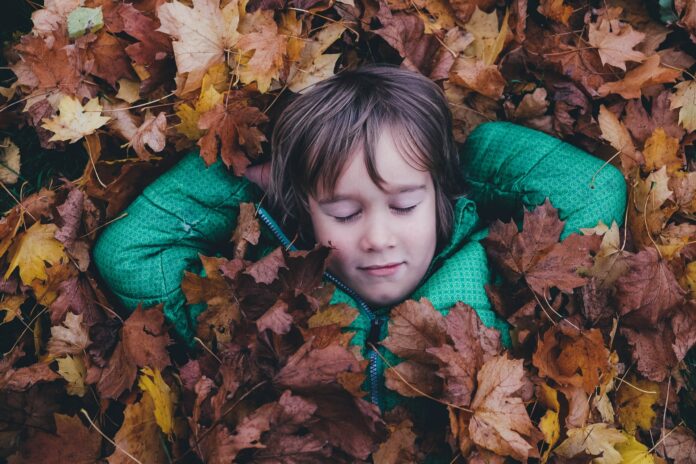 Kind entspannt im Blätterhaufen