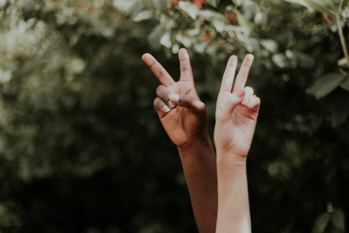 2 Hände strecken sich in die Luft und machen ein Peace-Zeichen