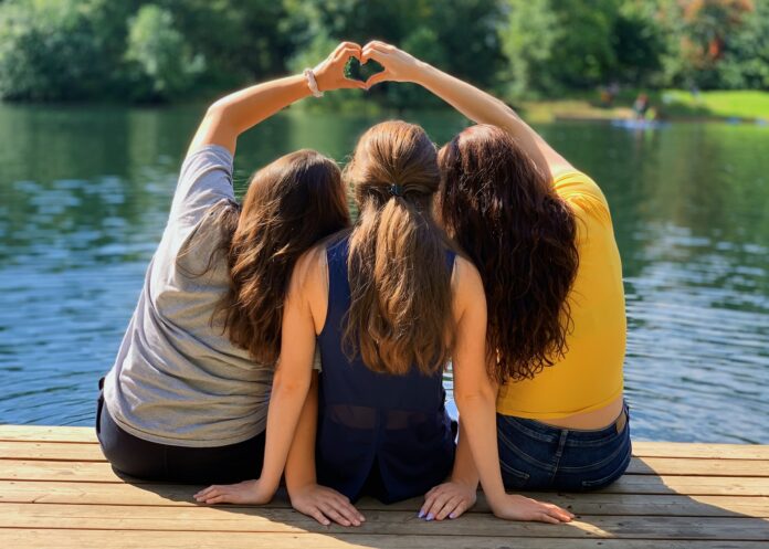 3 junge Frauen sitzen auf einem Steg am See