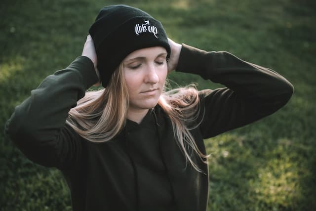 Junge Frau hält sich den Kopf und schließt die Augen