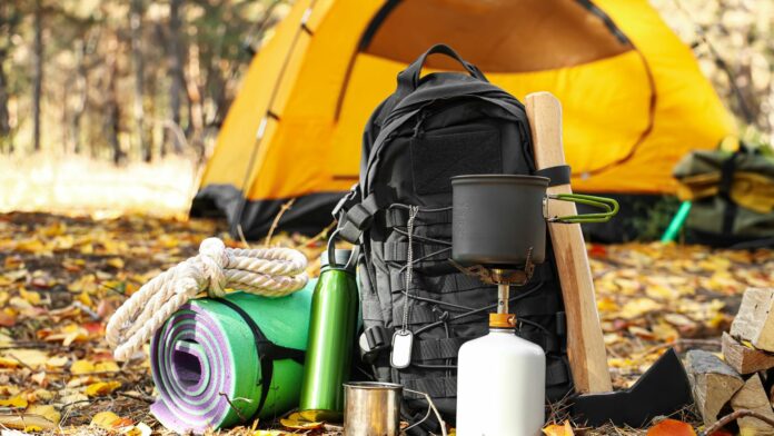 Schlafen im Wald – ein Zelt im Wald, davor Rücksack und Camping-Ausstattung