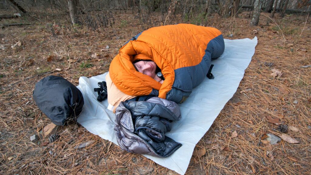 Schlafen im Wald – ein Mann in einem Schlafsack auf dem Waldboden